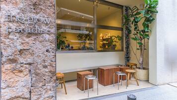 A storefront with a stone facade, a large window, and outdoor seating with stools and tables.