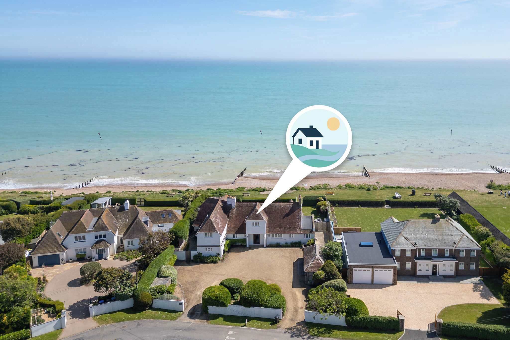 An aerial view of a coastal residential area with houses, a beach, and a clear sky.