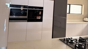 Eine moderne Küche mit eingebautem Backofen, einem Gaskochfeld und einem Fenster über der Arbeitsplatte.