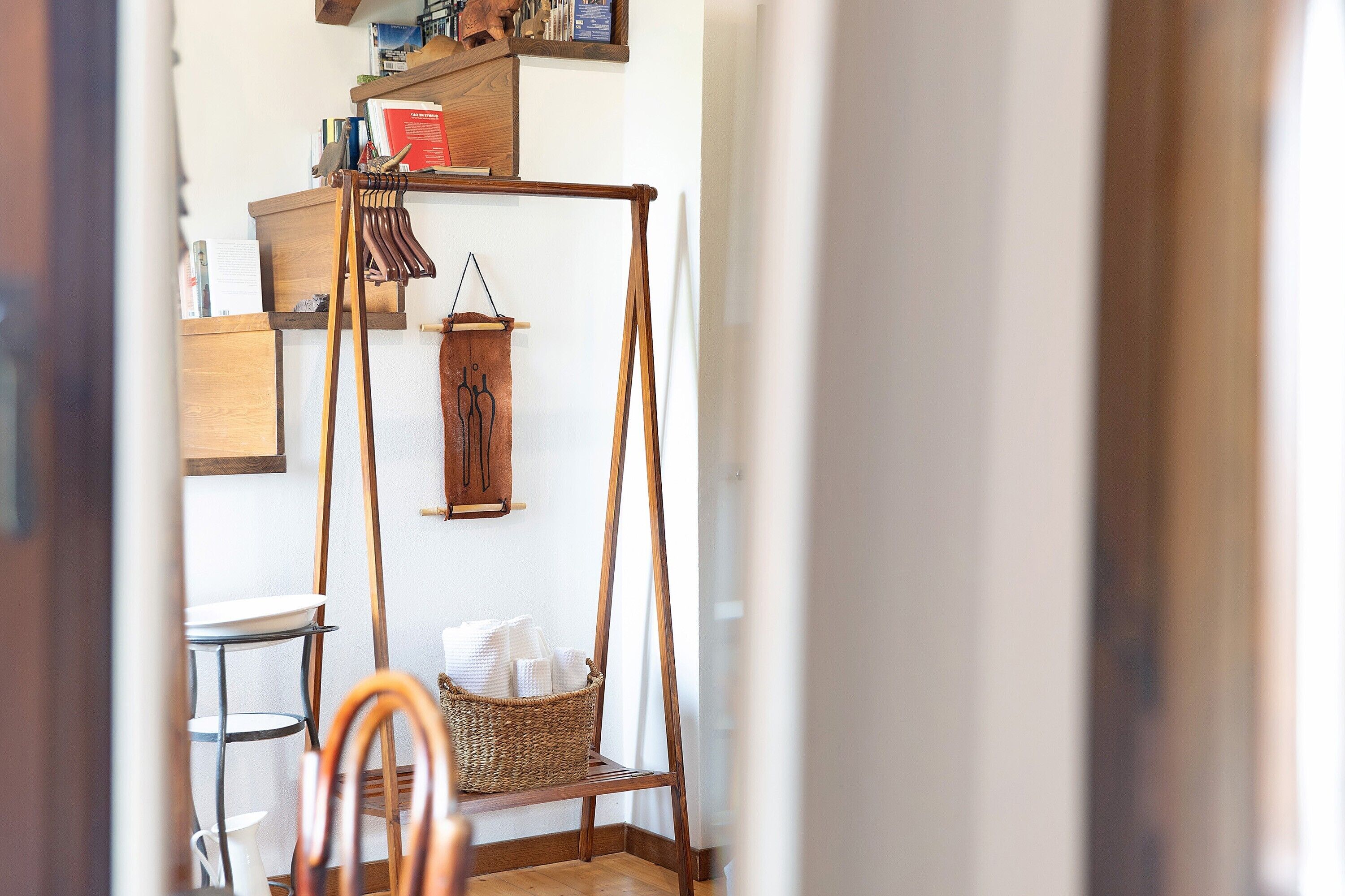 Een kamer met een houten stoel, een hangmand en een plank met boeken en een rode doos.