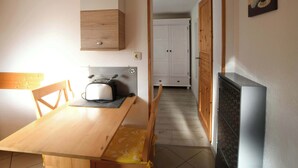 Een kleine keuken met een houten tafel, een broodrooster en een kast.