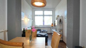 Een eethoek met een houten tafel, rieten stoelen en een hanglamp.