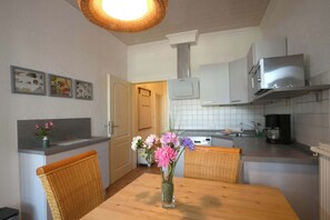 Cozinha com mesa de jantar, cadeiras, um vaso com flores, fogão e micro-ondas.