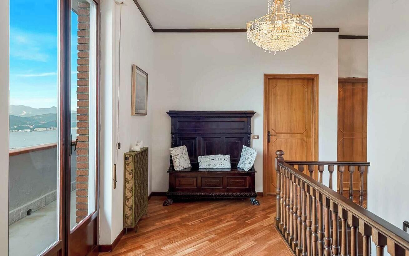 A hallway with a wooden bench, a chandelier, and a view of a body of water.
