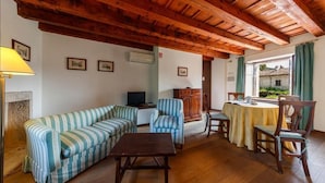 Una sala de estar acogedora con techo de madera, sofá a rayas, una mesita y un televisor.