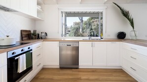 Una cocina moderna con armarios blancos, encimera de madera, horno integrado y lavavajillas.