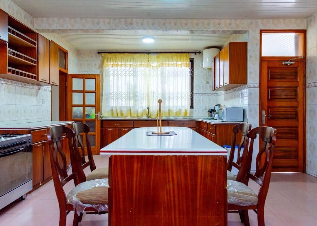 A kitchen with wooden cabinets, a central island, and a dining table with chairs.