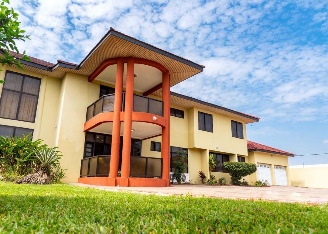 A two-story building with a central red structure, large windows, and a flat roof.