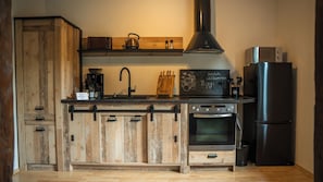 Eine Küche mit Holzausstattung, einer Kaffeemaschine, einem Wasserkocher, einer Mikrowelle und einem Kühlschrank.