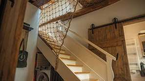 Eine Treppe mit Seilnetz, Holzboden und einem Waschbereich mit Waschmaschine.