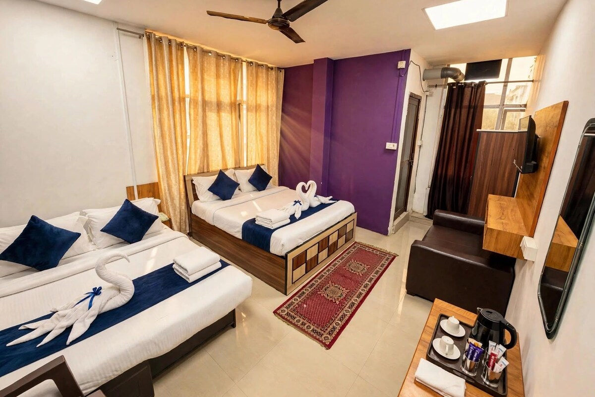 A hotel room with two beds, a ceiling fan, a television, and a coffee station.
