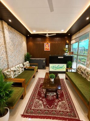 A reception area with a reception desk, two sofas, a coffee table, and a patterned rug. - The Kashi Palace (Varanasi)