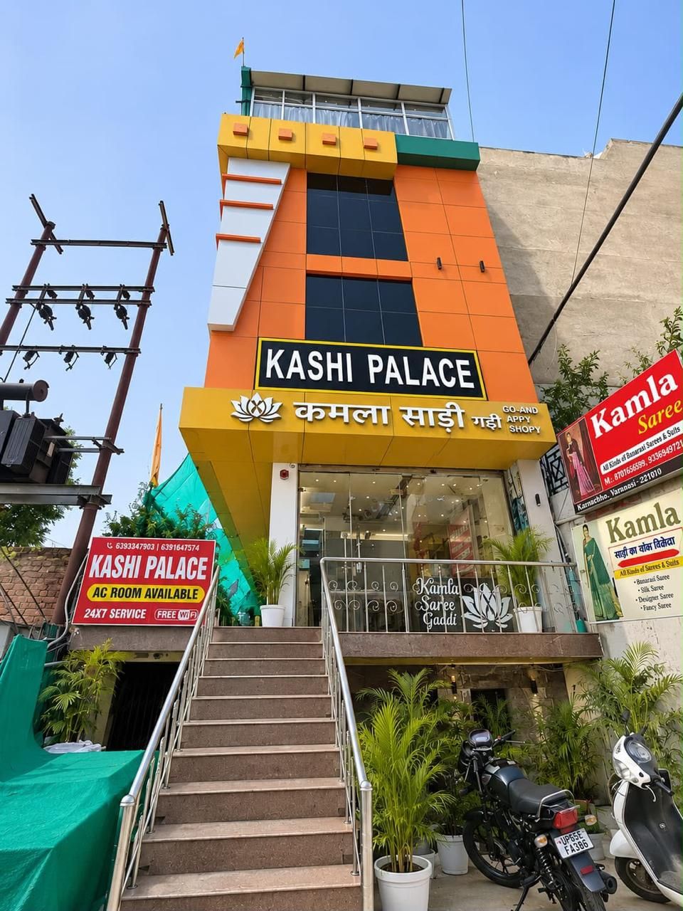 A multi-story building with a sign for 'Kashi Palace' and 'Kamla Saree' indicating a shopping area.