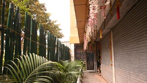 Une ruelle étroite, avec une porte fermée à droite, une clôture verte à gauche et un bâtiment sur lequel on peut lire l’inscription « KASAI PALACE ».