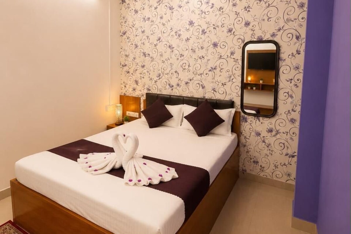 A neatly made bed with a headboard, a wall-mounted mirror, and a ceiling fan.