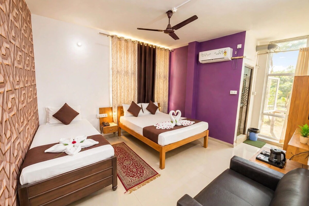 A hotel room with two beds, a ceiling fan, an air conditioning unit, a window with curtains, and a view of the outdoors.