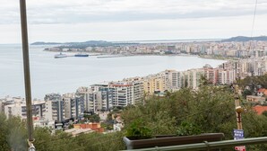 Eine Küstenstadtlandschaft mit Hochhäusern, einem Yachthafen und freiem Blick auf das Meer.