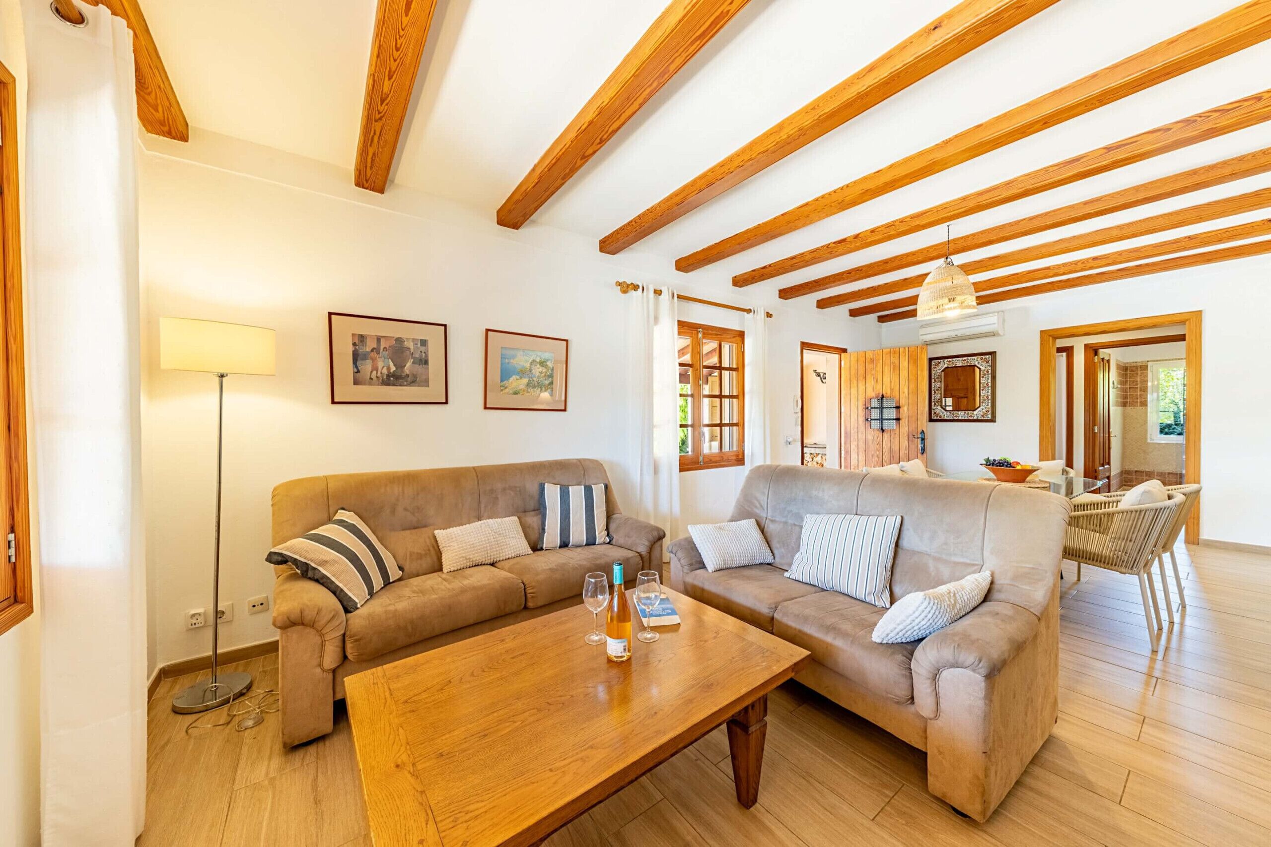 A spacious living room with wooden beams, two sofas, a coffee table, and a floor lamp.