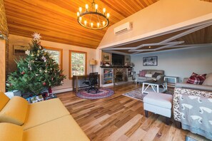 A cozy living room with a wooden ceiling, a Christmas tree, a fireplace, and a comfortable seating area. - The Craftsman - Handcrafted escape on Pond 2BR 2BA (Norfolk)