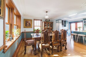 A dining room with a wooden table and chairs, a cabinet with glass doors, and a kitchen area in the background. - The Craftsman - Handcrafted escape on Pond 2BR 2BA (Norfolk)