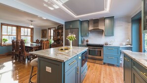A spacious kitchen with blue cabinets, a marble island, and wooden flooring. - The Craftsman - Handcrafted escape on Pond 2BR 2BA (Norfolk)
