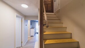 A staircase with wooden steps and a wooden handrail leading to a landing with a door. - The Craftsman - Handcrafted escape on Pond 2BR 2BA (Norfolk)