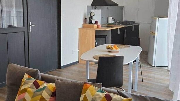 A compact living space with a sofa, a dining table, and a kitchenette.