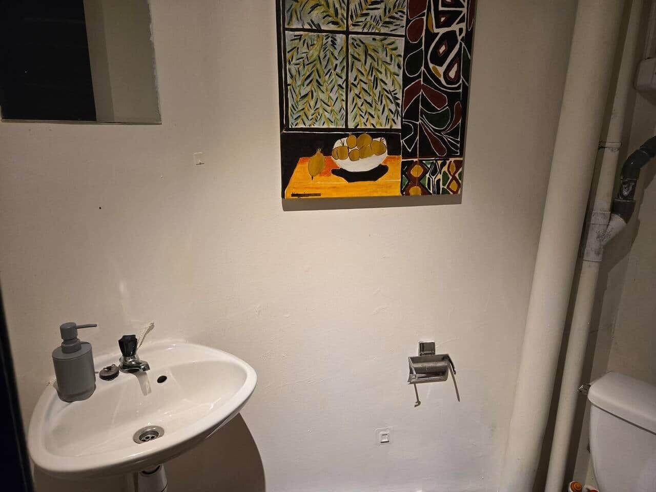A bathroom with a white sink, a soap dispenser, and a faucet. There is a window with a patterned view.