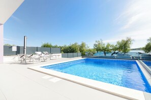Ein Pool auf dem Dach mit Liegestühlen und Blick aufs Meer.