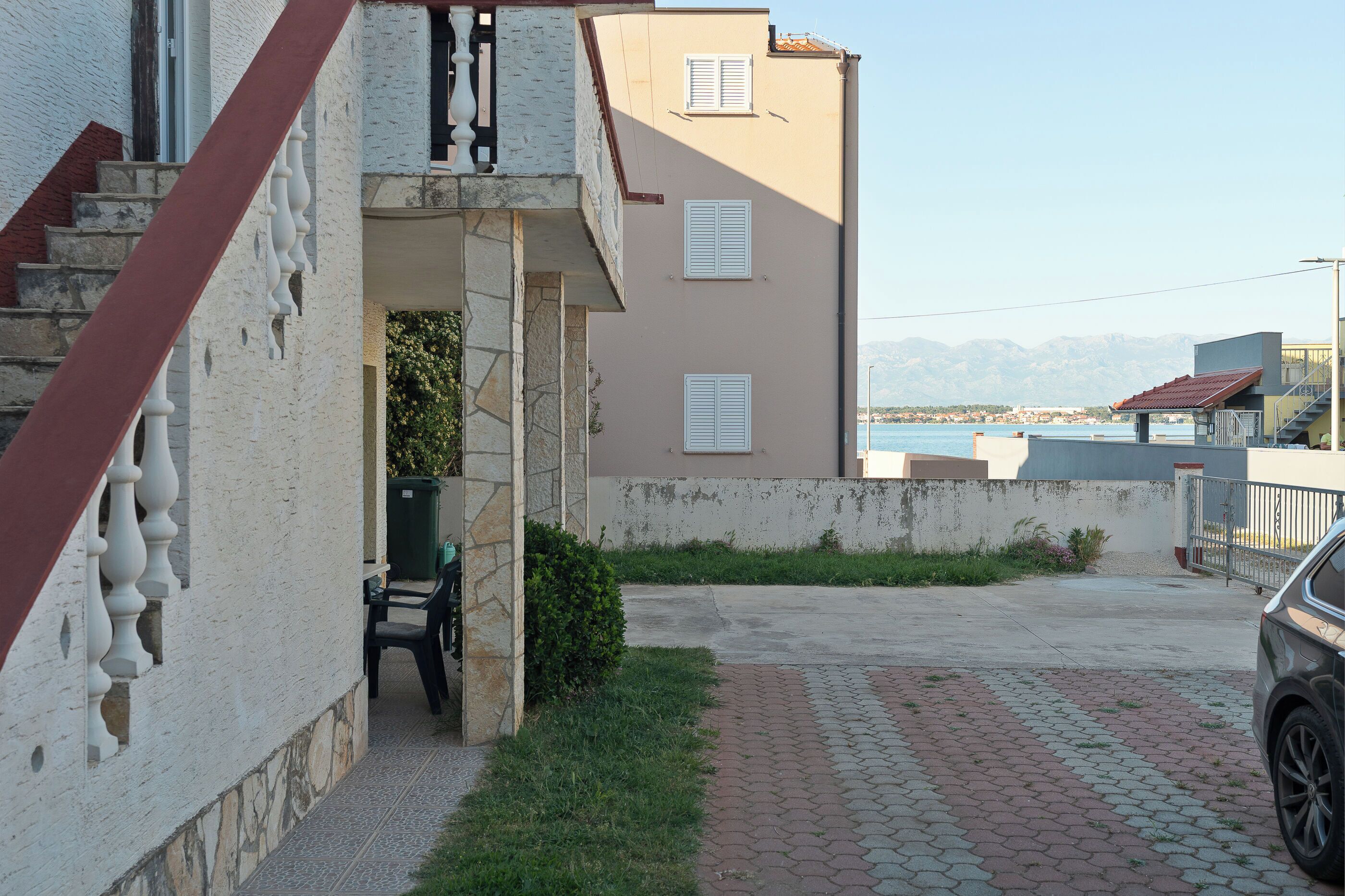 A residential building with a stone staircase, a balcony, and a view of the sea.