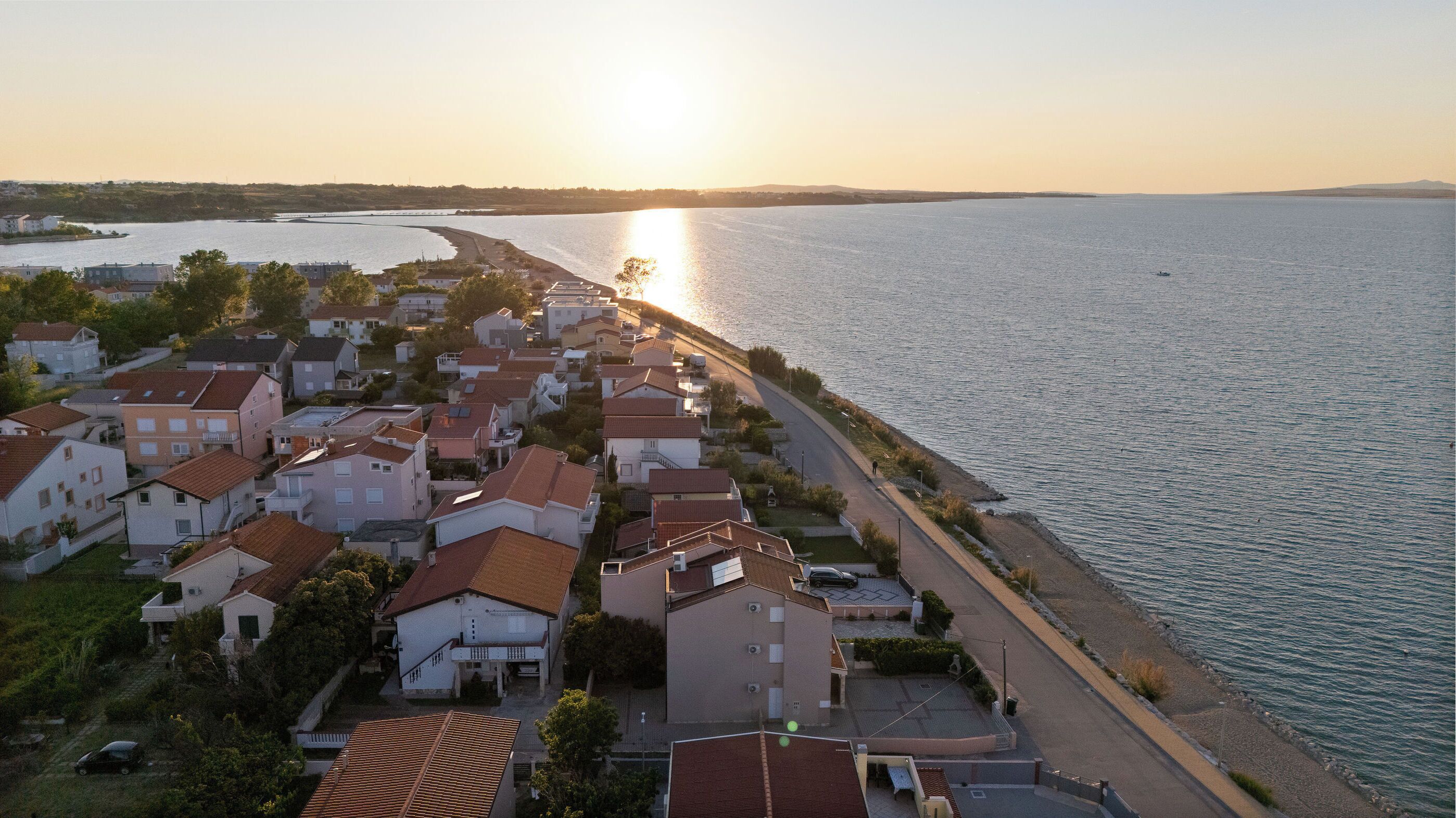 Una zona residencial costera con casas a lo largo del paseo marítimo y una vista despejada del mar.