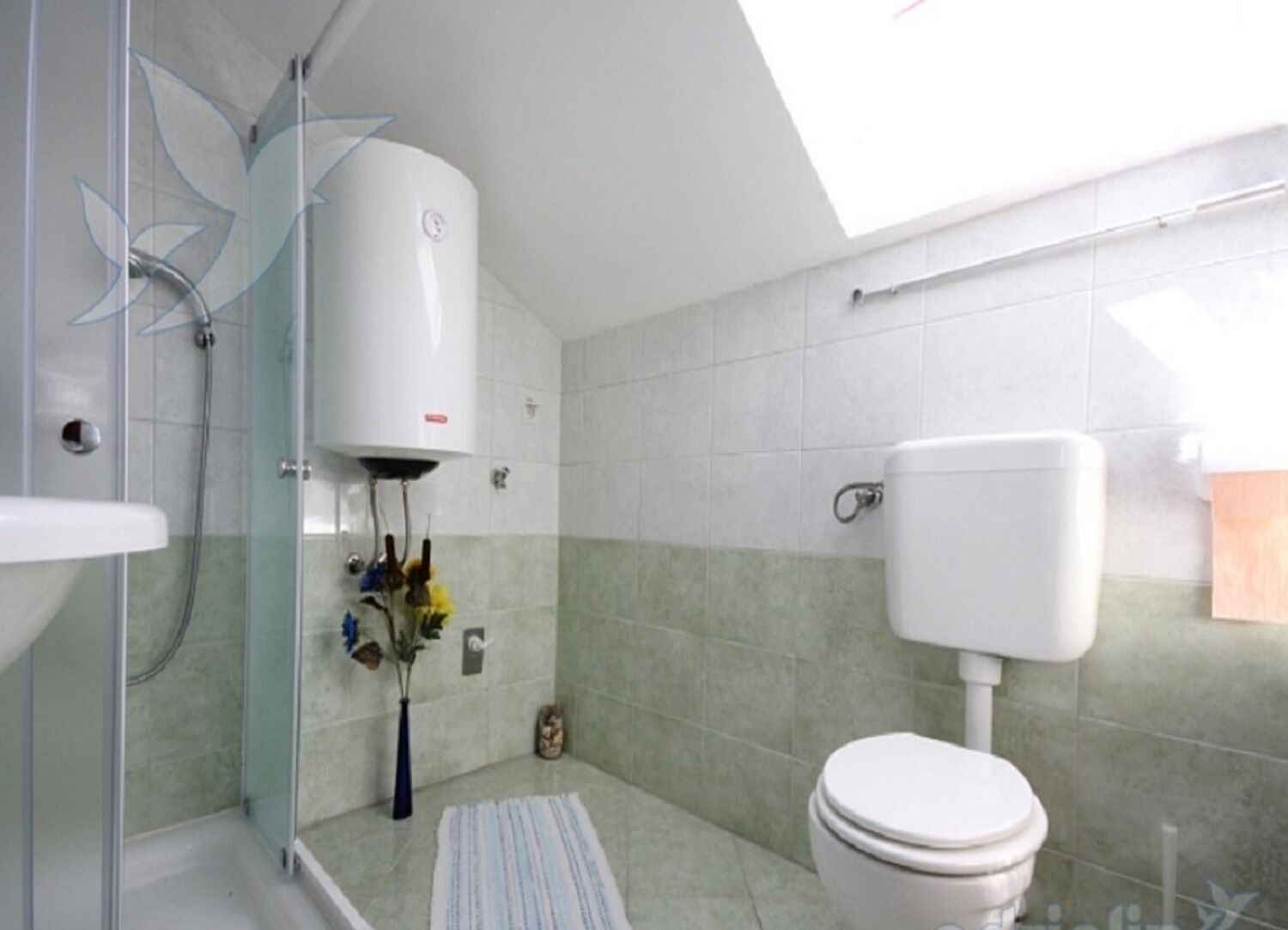 Een moderne badkamer met een douchecabine van glas, een wit toilet en een zichtbare boiler.