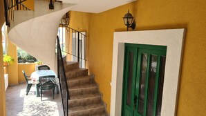 A staircase leading to a room with a green door, a table with chairs, and a view of the outside. - Apartments Stosa (Nin)