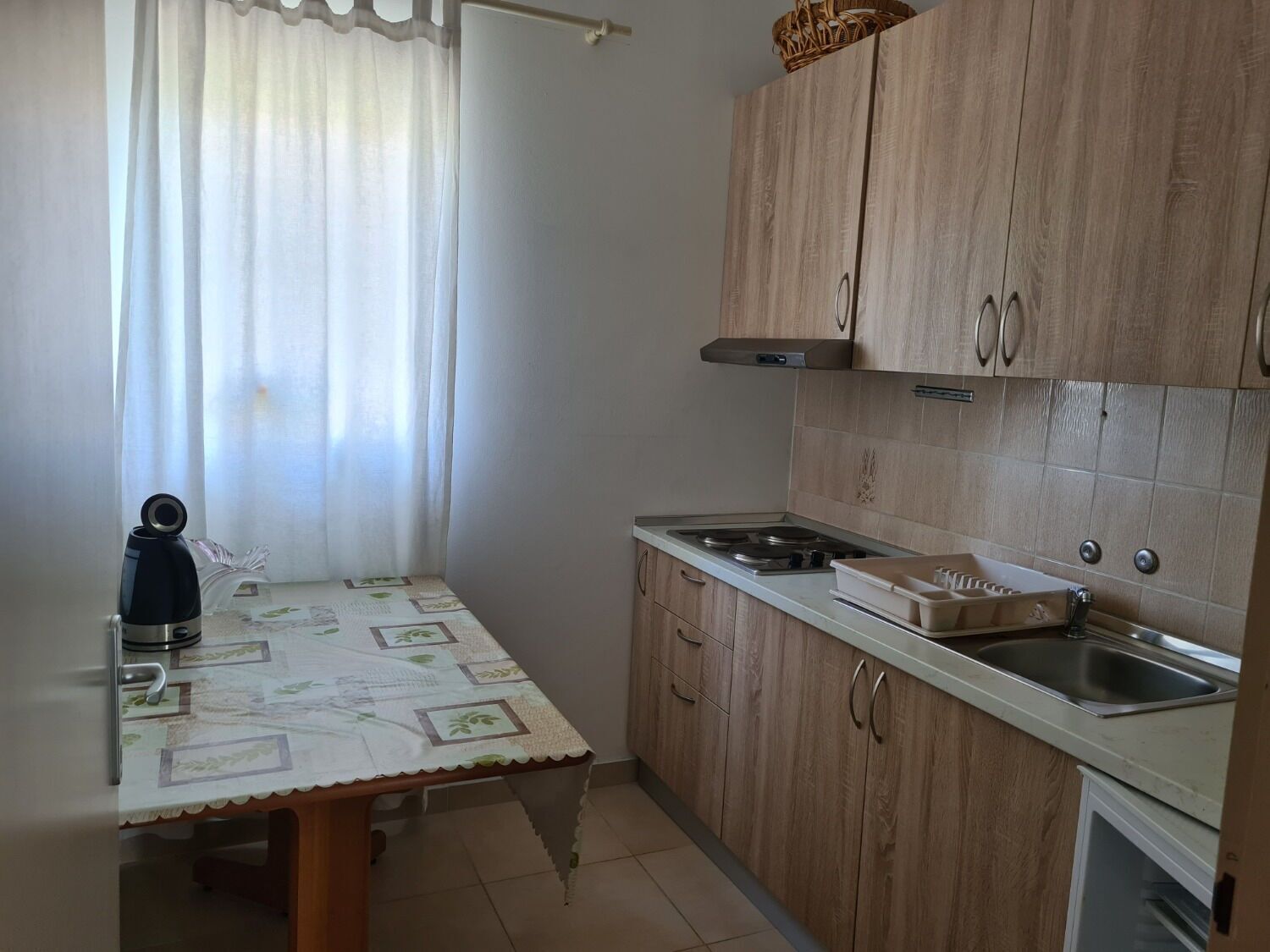 A small kitchen with wooden cabinets, a stainless steel sink, and a table with a placemat.