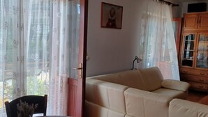 Una sala de estar con un sofá color beige, una mesa de comedor con un florero y un aparador con puertas de vidrio.
