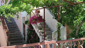 A staircase with a metal railing, surrounded by lush greenery and flowering plants. - Apartments Brti (Supetar)