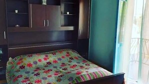 A bedroom with a bed, dark wooden wardrobe, and a window with curtains. - Apartments Brti (Supetar)