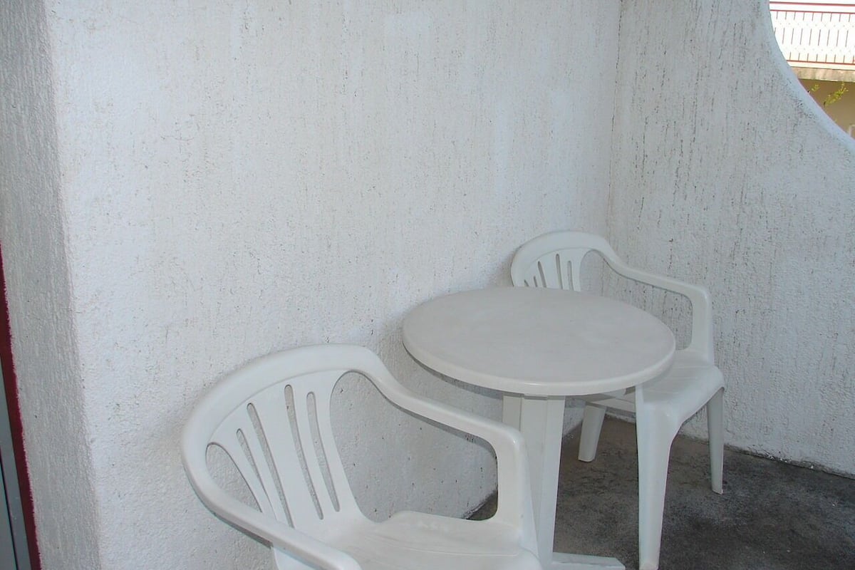A small, white, round table with two white plastic chairs.