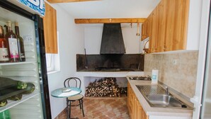 A compact kitchen with a wood stove, a sink, and a small dining table. - Apartments Dome (Trogir)
