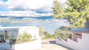 A coastal property with a view of the sea, a covered outdoor seating area, and a white building with a garden. - Apartments Dome (Trogir)