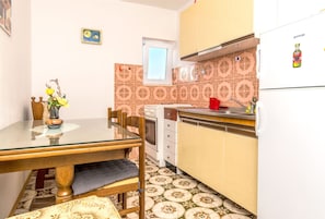 Appartement (A3) | Privékeuken | Een koelkast, een oven, een kookplaat, kookgerei, borden en bestek