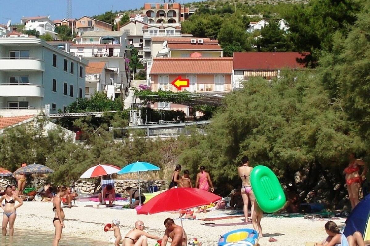 Een strand met mensen, parasols en gebouwen op de achtergrond.