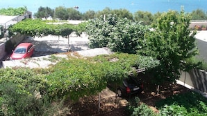 A residential area with a view of a lake, a red car, and a black car parked in a driveway. - Apartments Andelka (Marina)