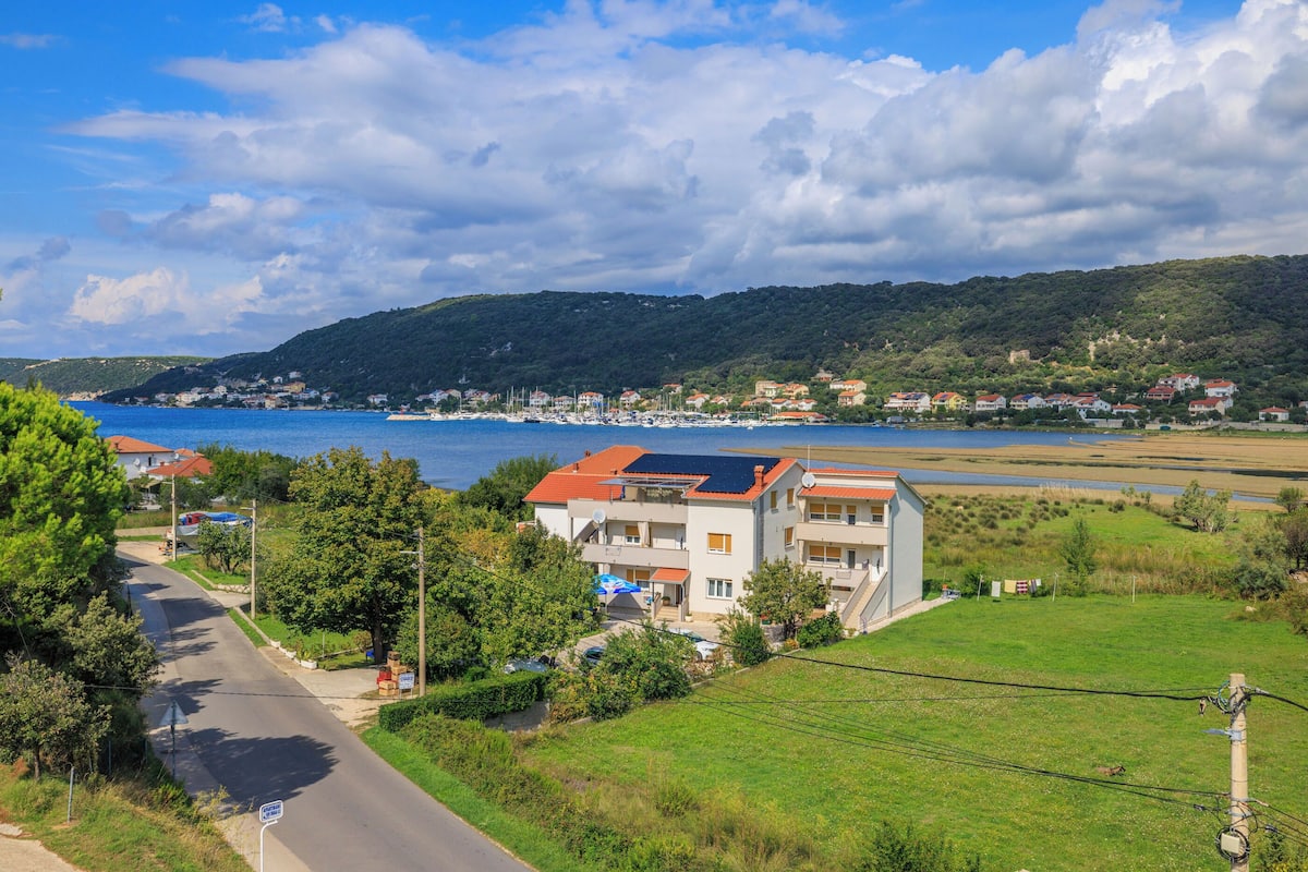 Un quartier résidentiel situé sur la côte, avec des maisons, une route et une vue sur la mer.