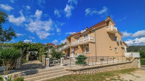A multi-story building with a balcony, a stone staircase, and a flag. - Apartments Mig (Rab)