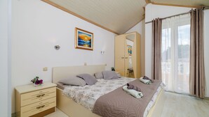 A bedroom with a bed, a nightstand, a dresser, a mirror, and a window with curtains. - Apartments Mig (Rab)