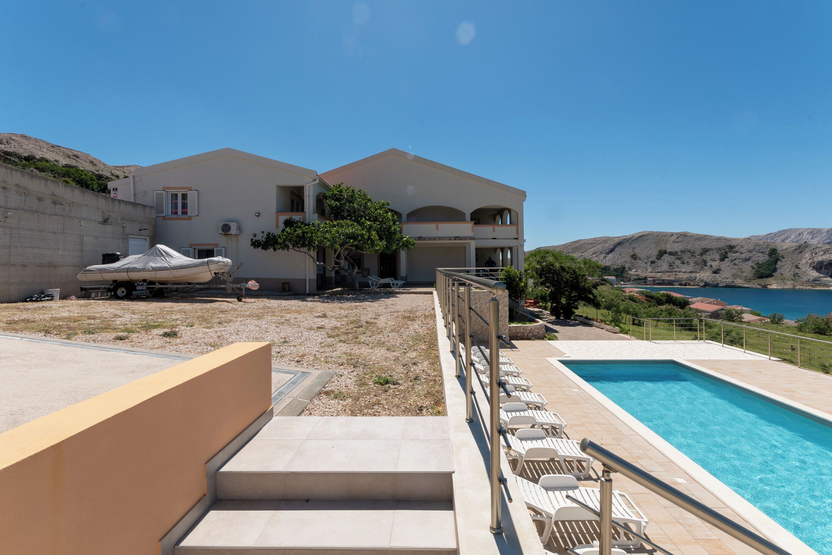 A two-story building with a swimming pool, outdoor seating, and a view of the sea.