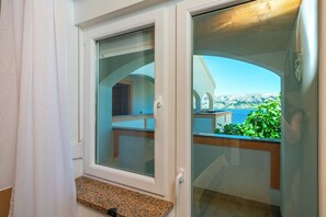 A room with a sliding glass door leading to a balcony with a view of mountains and greenery. - Apartments Poolhouse (Novalja)