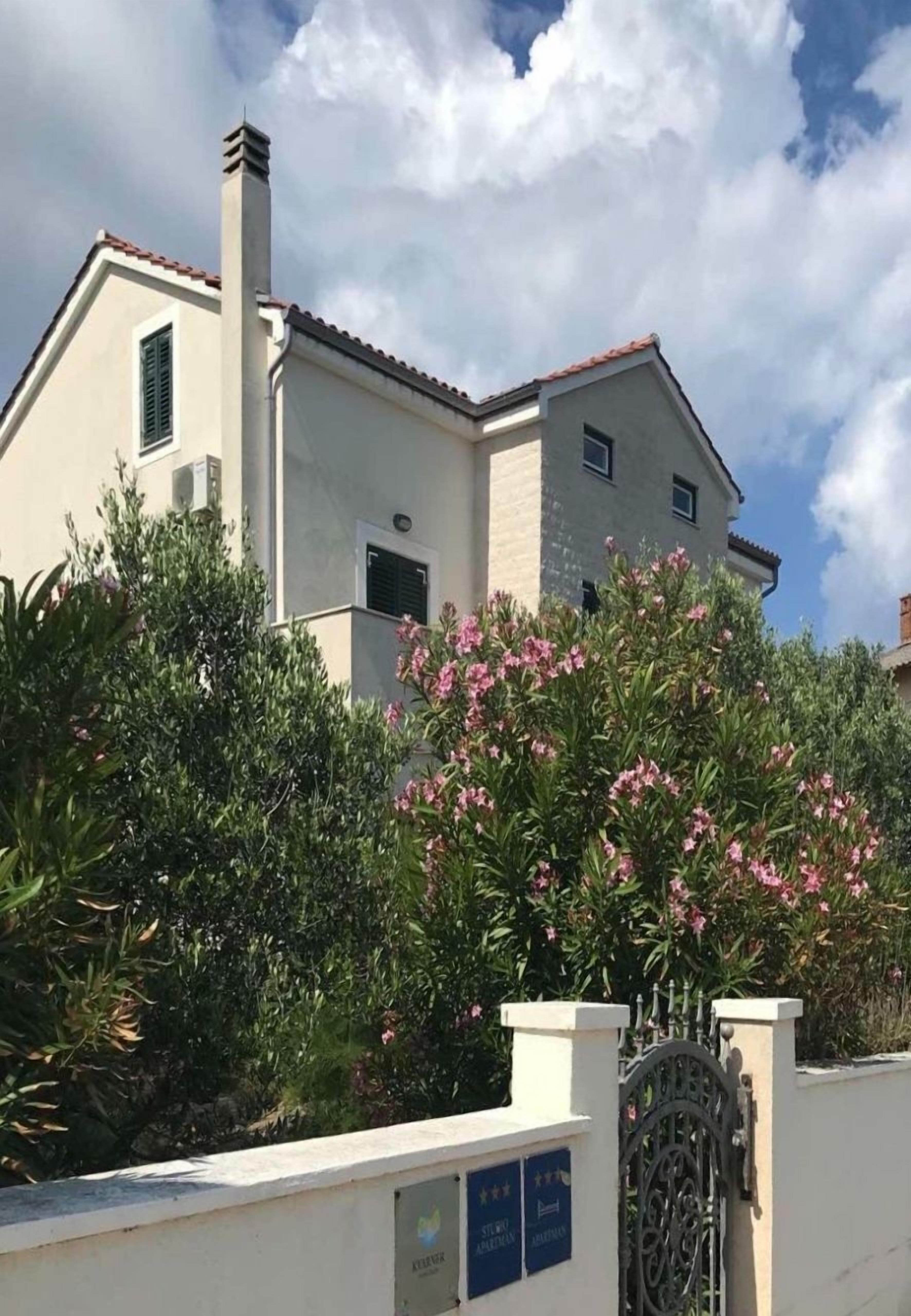 Un bâtiment à deux étages, doté d’une façade beige, d’une cheminée et d’une entrée fermée par un portail.