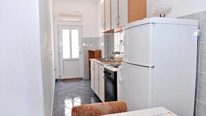 A compact kitchen with a refrigerator, stove, and sink. - Apartments Draga (Novalja)